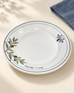 Detalhe do prato raso branco Family Cook com ramo de oliveira e detalhe floral azul e amarelo
