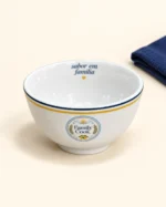 Detalhe da tigela funda branca Family Cook com selo frontal e filetes azul e amarelo